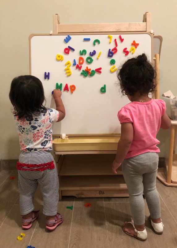 Children arrange letters on a magnetic board